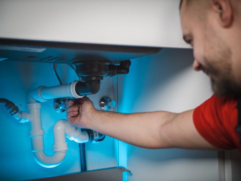 Plumber working on pipework under a sink