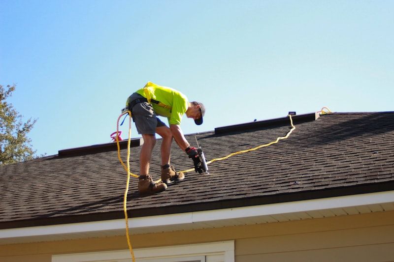 Roofer fixing shingles on a pitched roof
